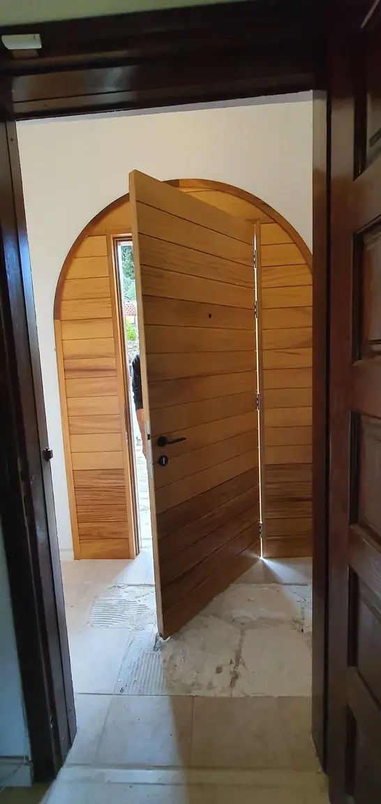 The arched iroko door opened, seen from inside the hallway