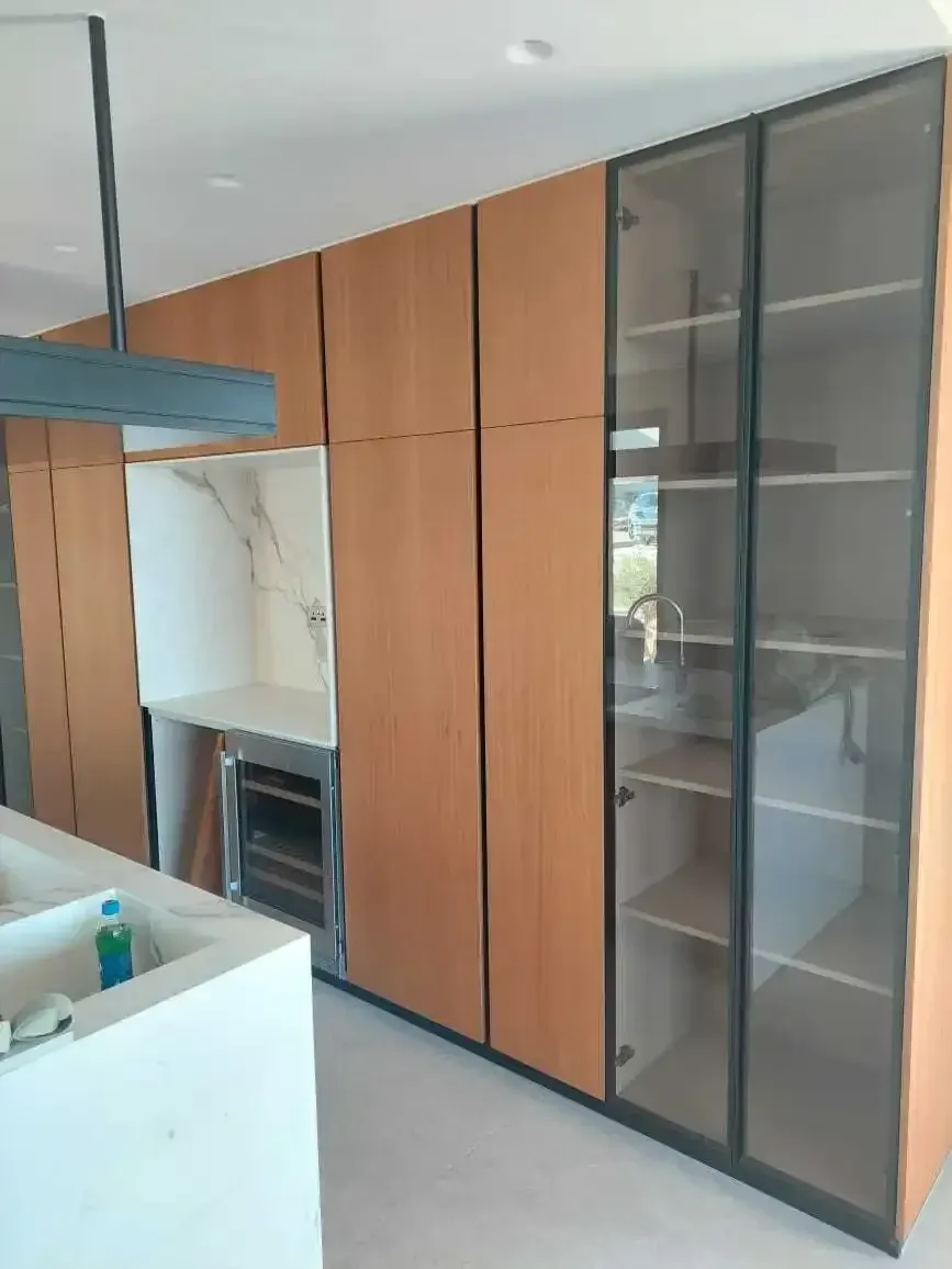 Built-in wine cooler and marble-effect niche between the wood tall units