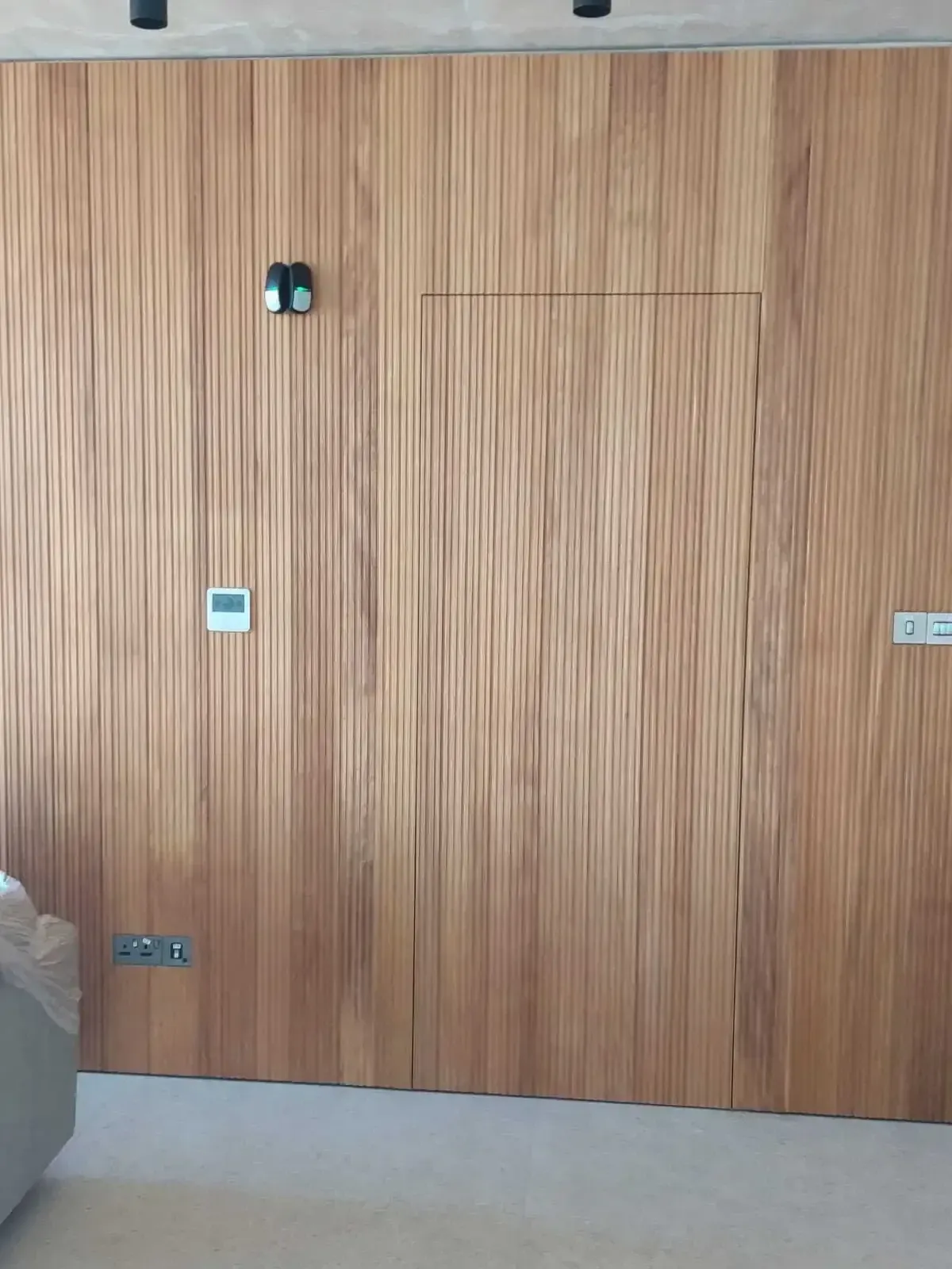 Full-height fluted wood wall cladding with a hidden door set flush into the panelling