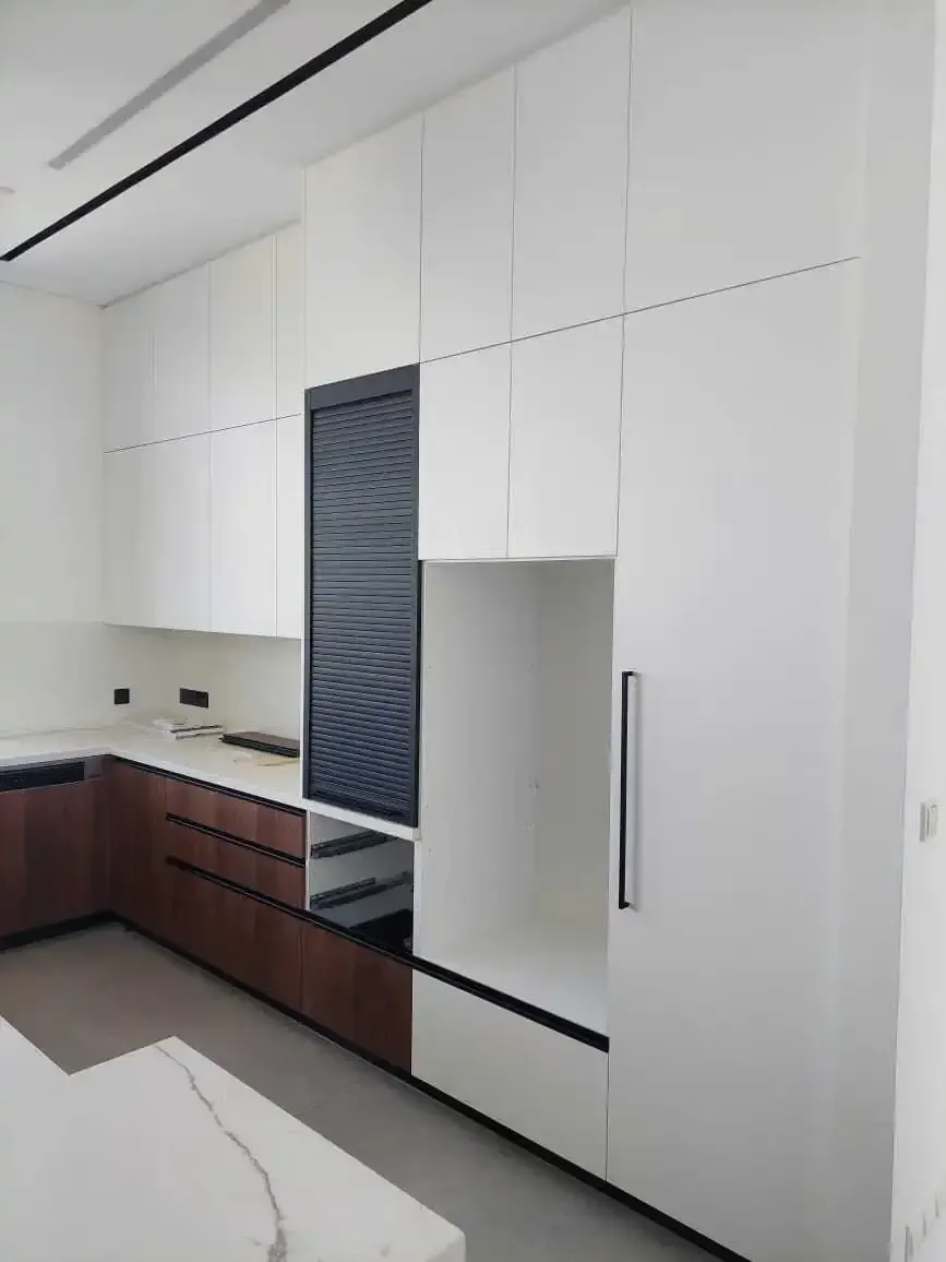White and walnut kitchen with a roller-shutter appliance garage and built-in tall units