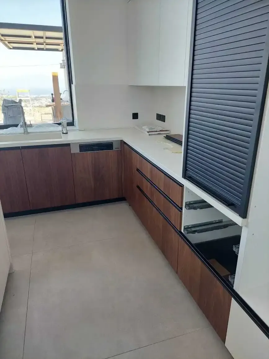 Walnut base units and white stone worktop under a sea-view window