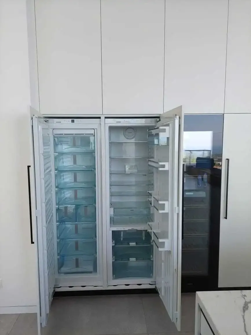 Integrated side-by-side fridge and freezer behind white tall unit doors