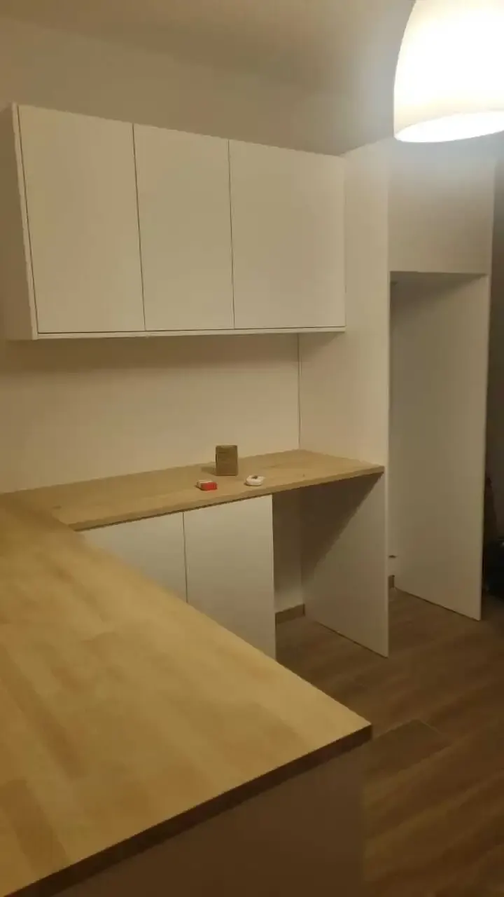 White L-shaped kitchen with solid wood worktops and a tall housing unit