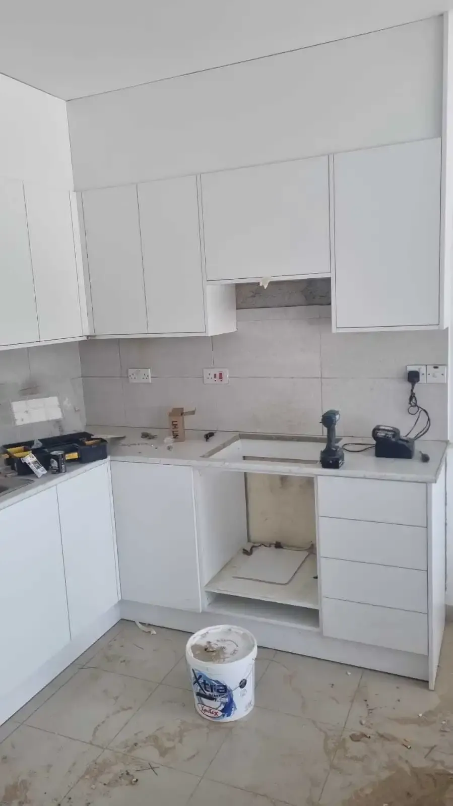 Compact white handleless kitchen with wall units to the ceiling and a grey worktop