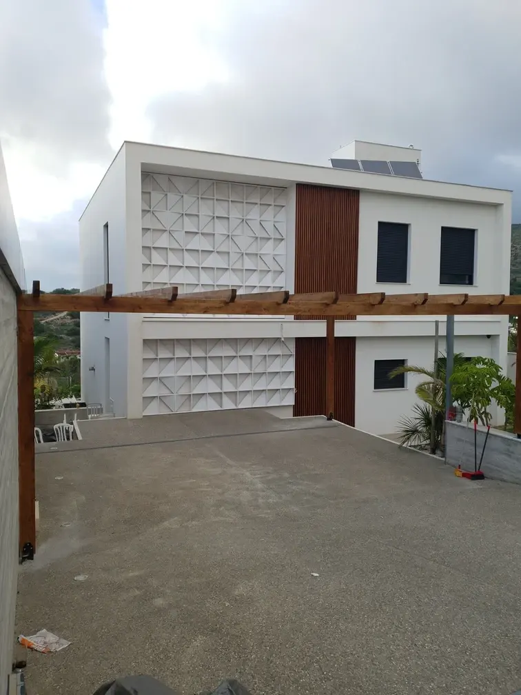 Dark-stained wooden pergola on the terrace of a modern villa with timber and concrete facade