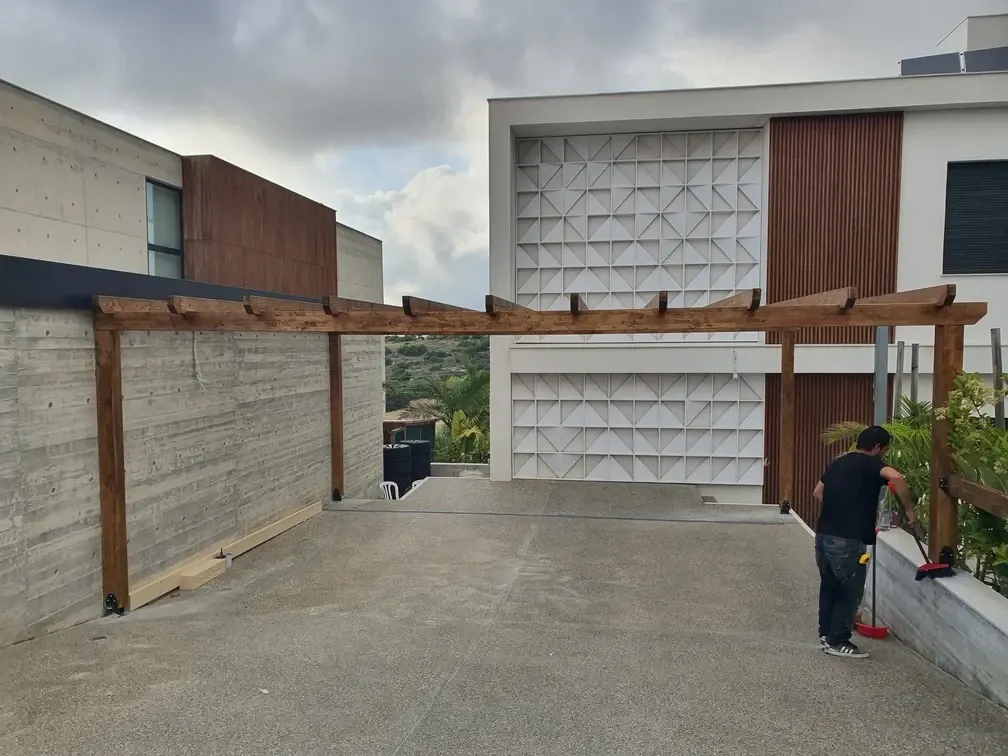 Pergola beams fixed along the board-formed concrete wall of the terrace